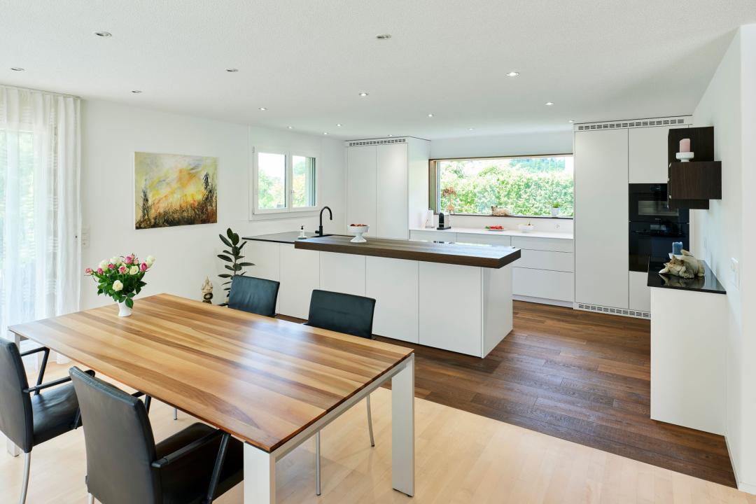 Weisse Küche mit Holzakzenten und Halbinsel in Laupen