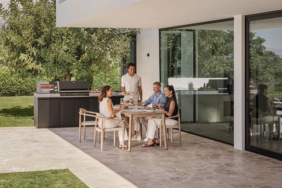 Familie grillt gemeinsam an einer Miele Gartenküche im Sommer